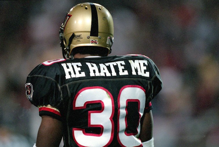 Een voetballer toont de achterkant van zijn shirt met de tekst He Hate Me' boven het nummer 30 in X.F.L.' above the number 30 in X.F.L.