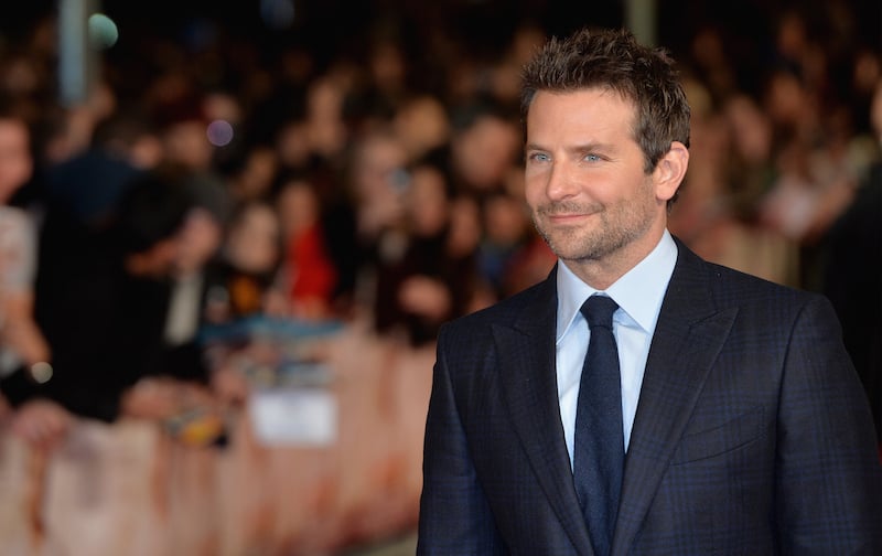 Bradley Cooper is smiling on the red carpet.