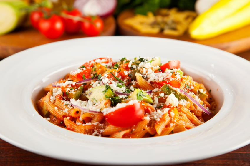 pâtes végétariennes aux poivrons, tomates, courgettes et fromage dans un bol blanc