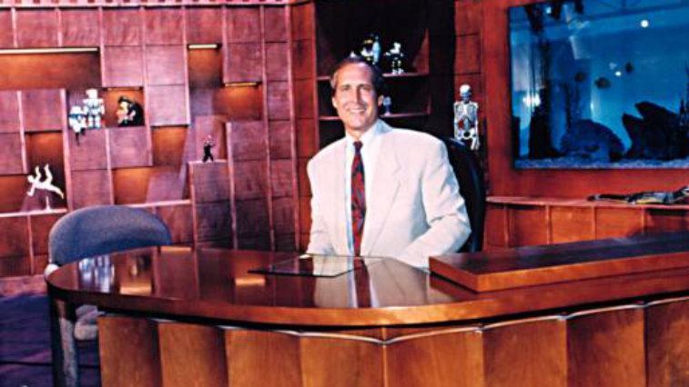 Il conduttore Chevy Chase alla sua scrivania in The Chevy Chase Show