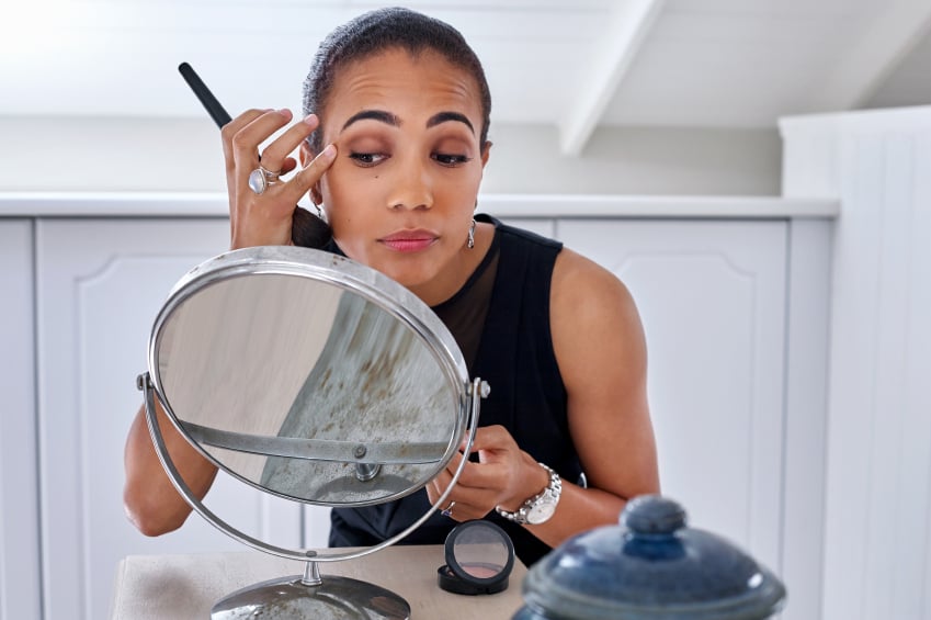 woman doing makeup in front of a mirror