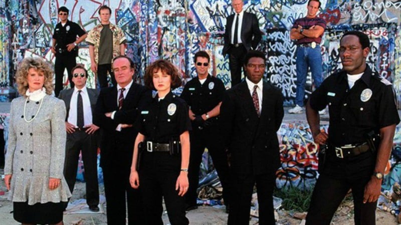 Grupa 11 osób, niektórzy policjanci stojący przed graffiti