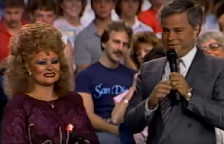 Tammy Faye staat met echtgenoot Jim Bakker die een microfoon vasthoudt voor een studiopubliek's holding a microphone in front of a studio audience