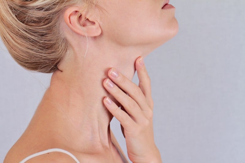 Woman touching her throat where her thyroid gland is