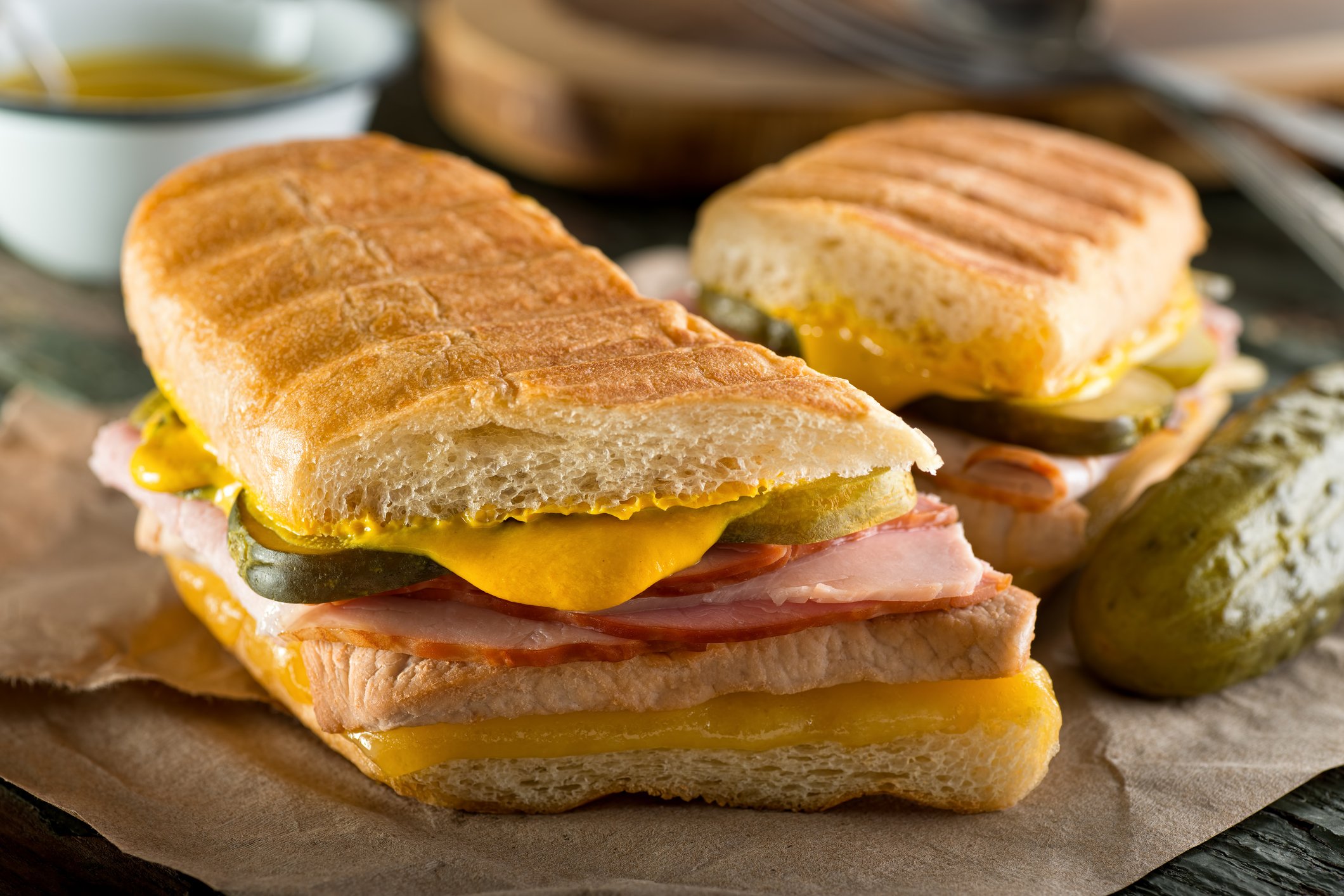 An authentic cuban sandwich on pressed medianoche bread with pork, ham, cheese, pickle, and mustard.