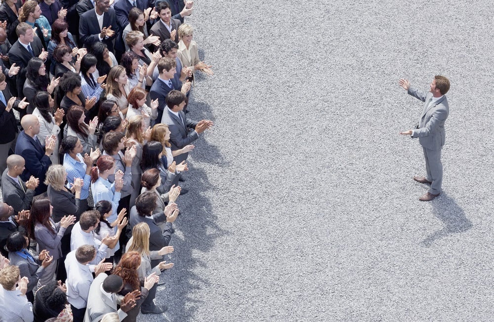 Businessman addressing clapping crowd