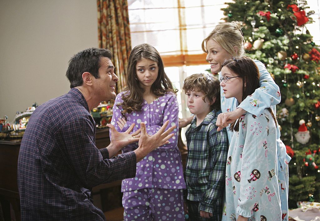 The Dunphy family in pajamas in front of a Christmas tree in a scene from one of the 'Modern Family' Christmas episodes.