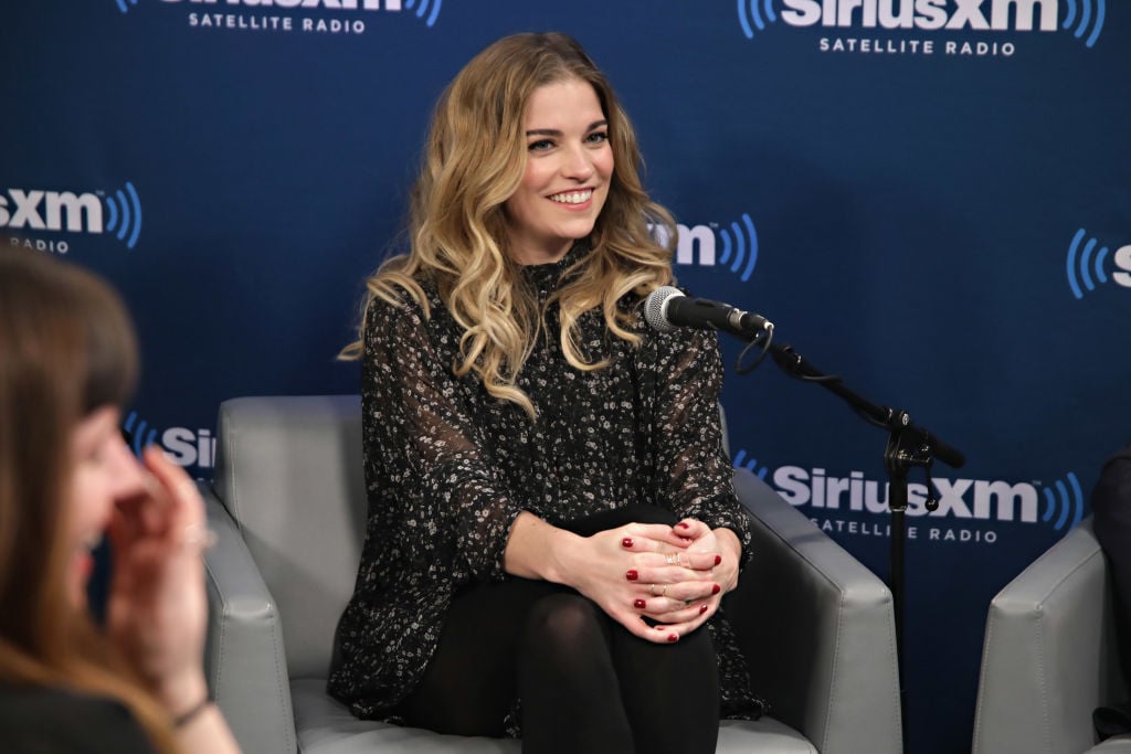 Annie Murphy smiling, seated on a chair