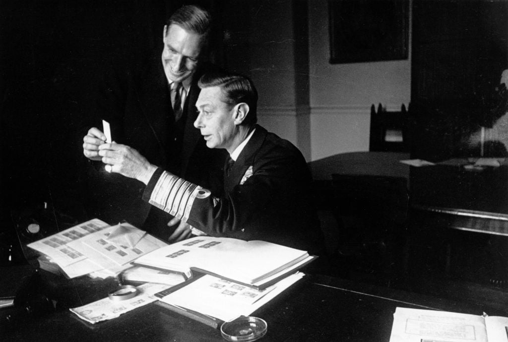 King George VI looks through stamps with the Curator of the Royal Stamp Collection