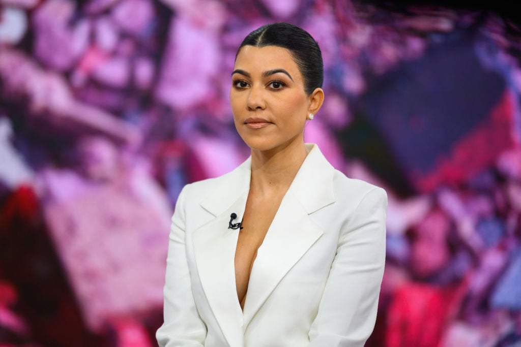 Kourtney Kardashian in front of a multicolored background