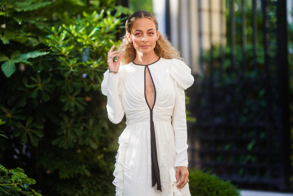 Nicole Richie wearing a white dress with black lining, standing in a garden