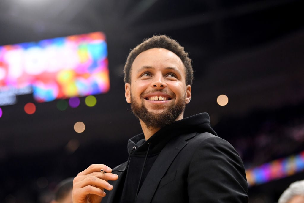 Steph Curry smiling, looking over the camera