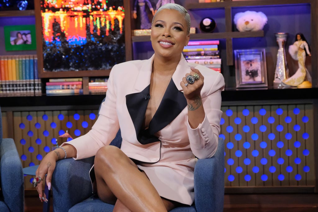 Eva Marcille smiling, sitting in a chair wearing a pink dress