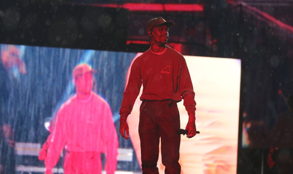 Travis Scott smiling on stage, looking off to the side