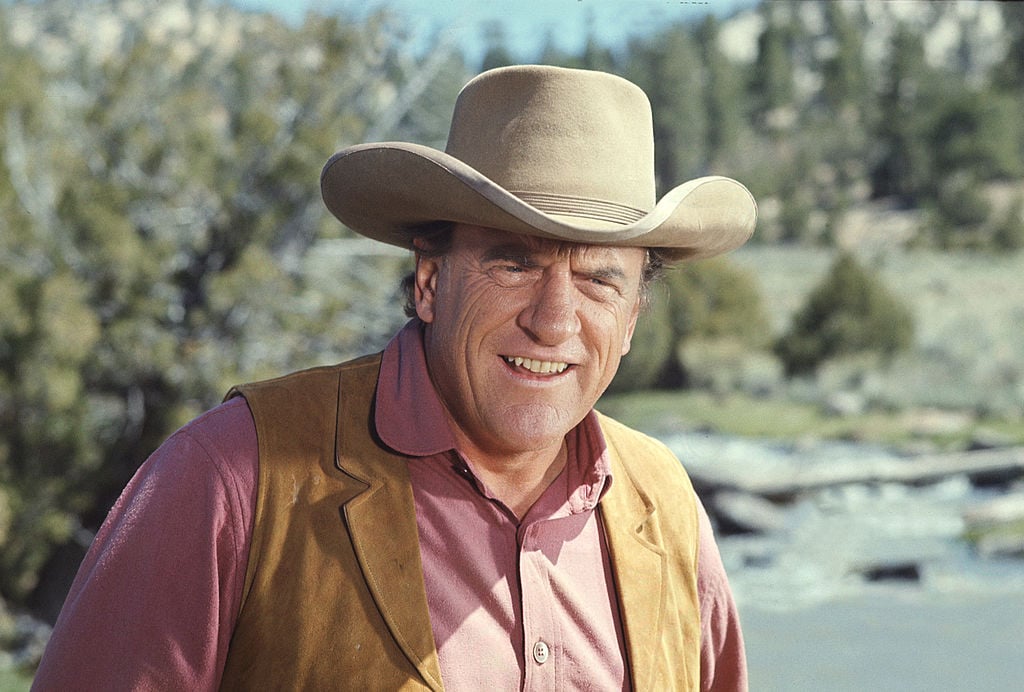 James Arness as Marshal Matt Dillon smiling in front of a blurred desert