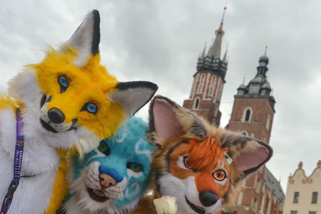 Members of different Furry Fandom Conventions pose for a photo at Adam Mickiewicz's monument in Krakow Main Market Square