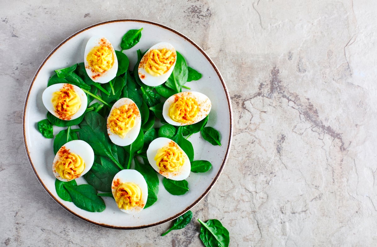 Plate of deviled eggs with spinach on a marbled background