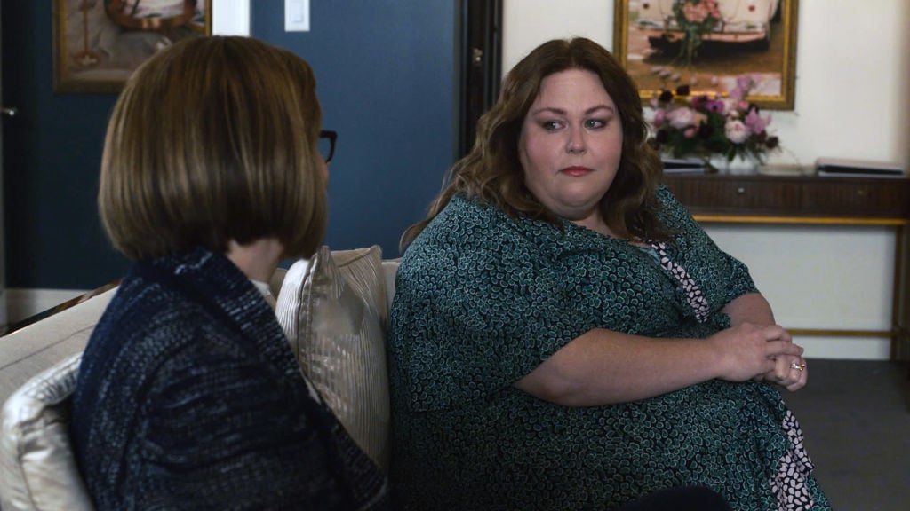 Mandy Moore as Rebecca, Chrissy Metz as Kate sit on a couch to talk. Kate is in a green dress and looks concerned.