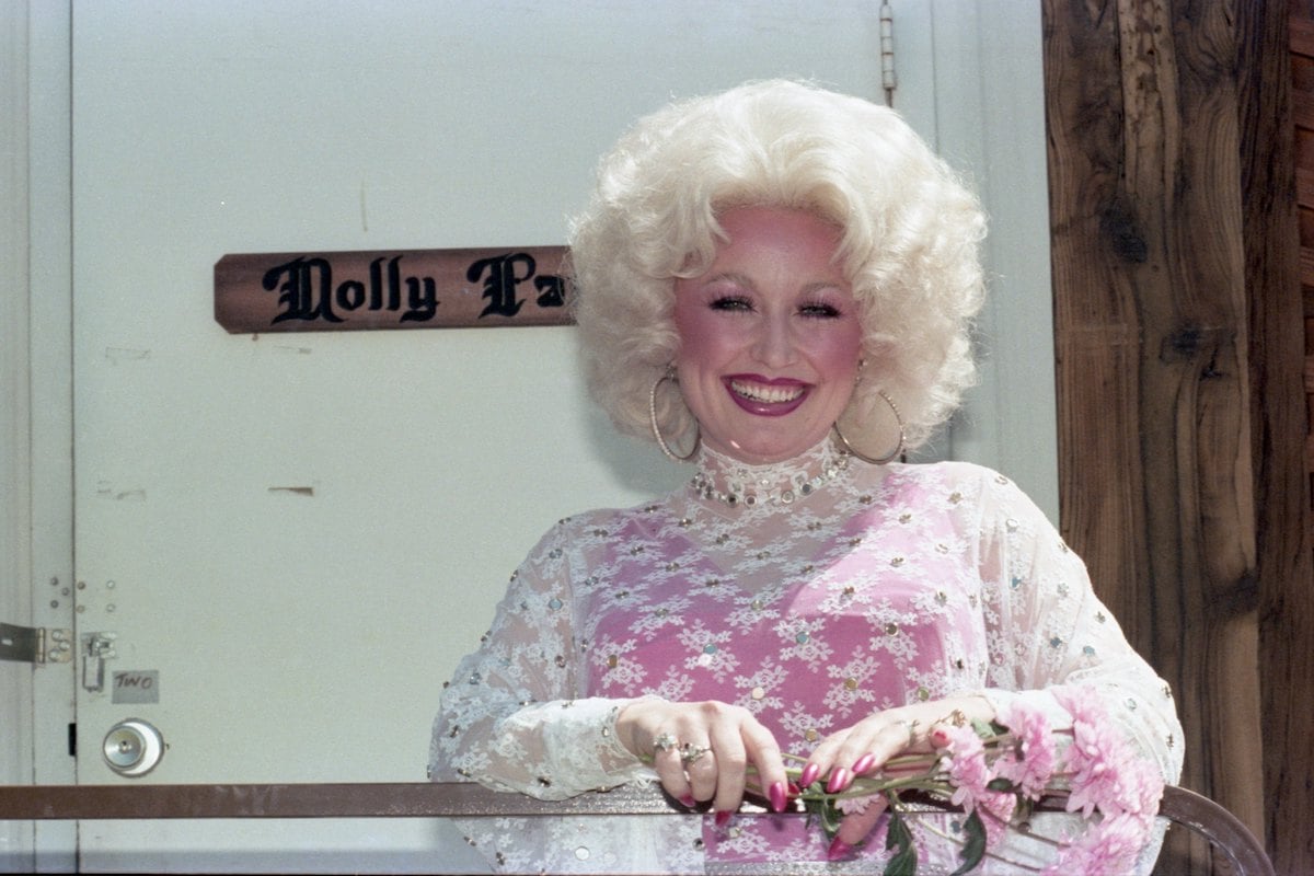 Dolly Parton smiles dressed all in black and holds her Hitmaker Award during the Billboard Women In Music 2020 event