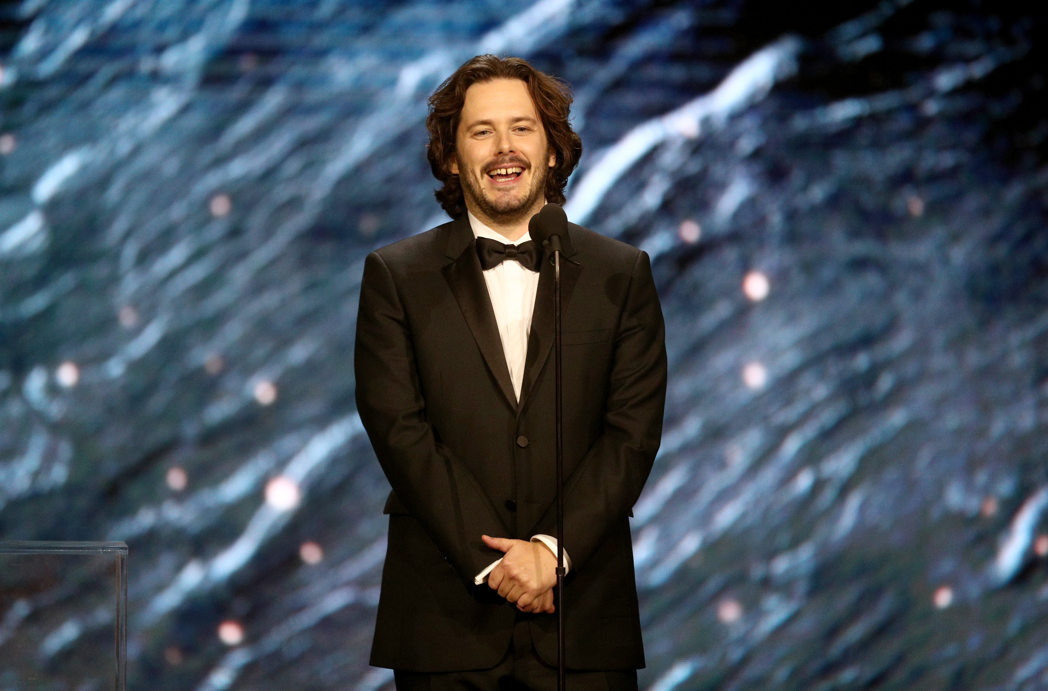 Edgar Wright in a suit and bow tie presenting an award.