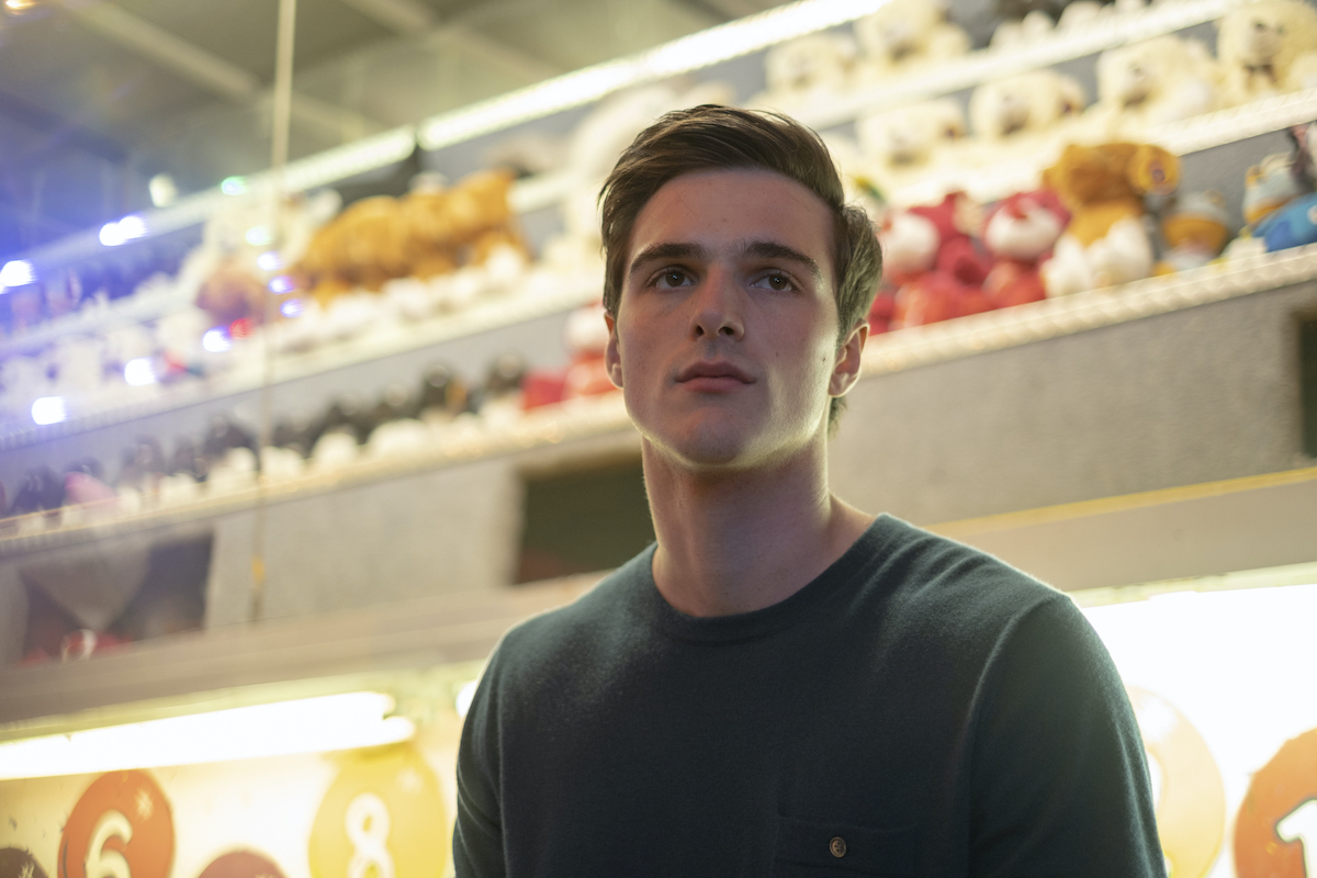 'Euphoria' Season 2's Jacob Elordi as Nate Jacobs. Elordi returns for season 2, currently in production. He says the new season of 'Euphoria' is 'a completely different show.' In this photo from season 1, he stands in a carnival booth at night wearing a green crew neck shirt. He looks off into the distance with a blank stare on his face.