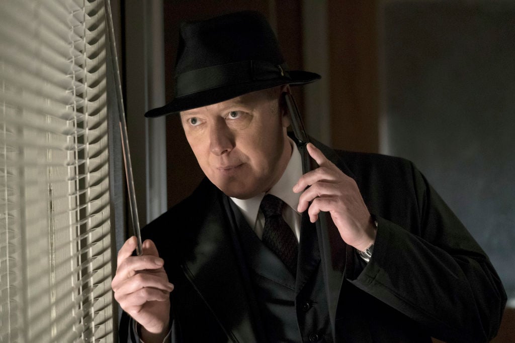 James Spader as Raymond 'Red' Reddington peers out the window while speaking on a phone.