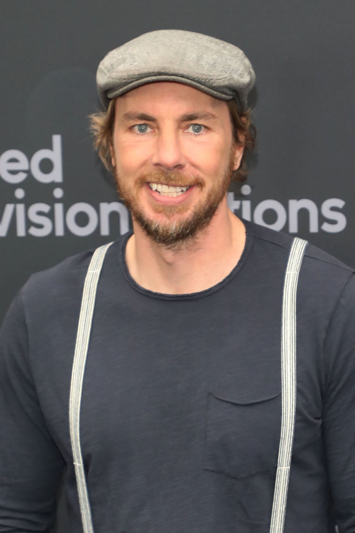 Dax Shepard wears a hat and suspenders at an event.