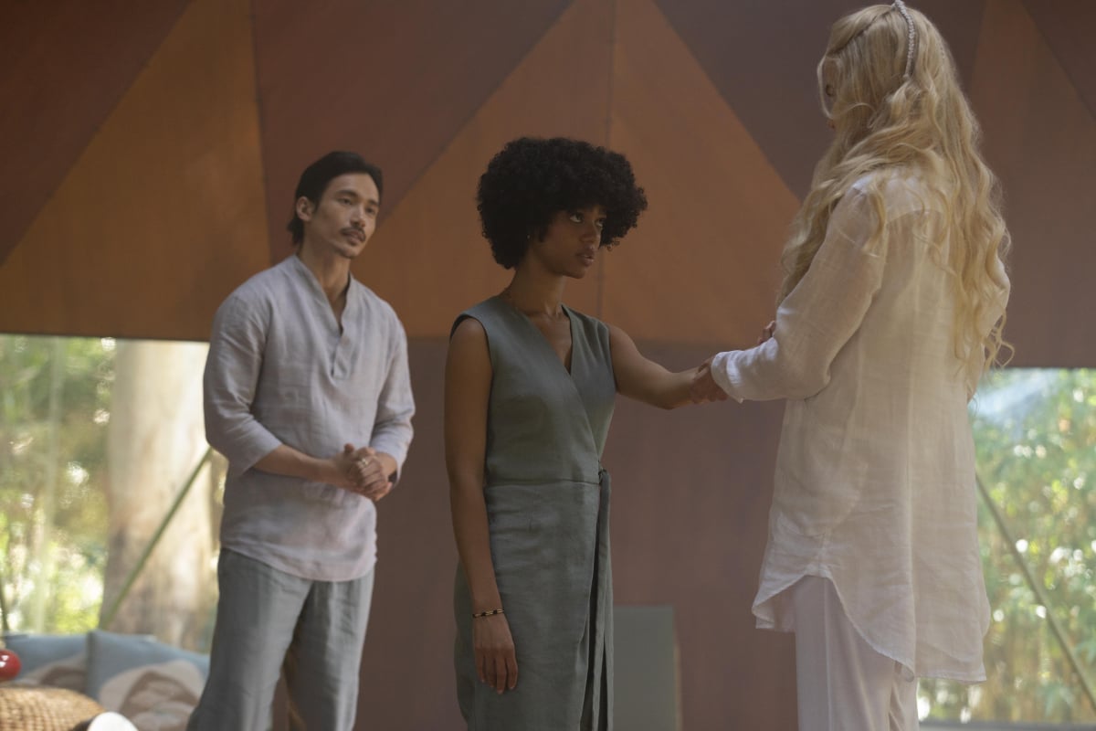 Yao stands behind Delilah while Masha holds Delilah's hand in Nine Perfect Strangers. 