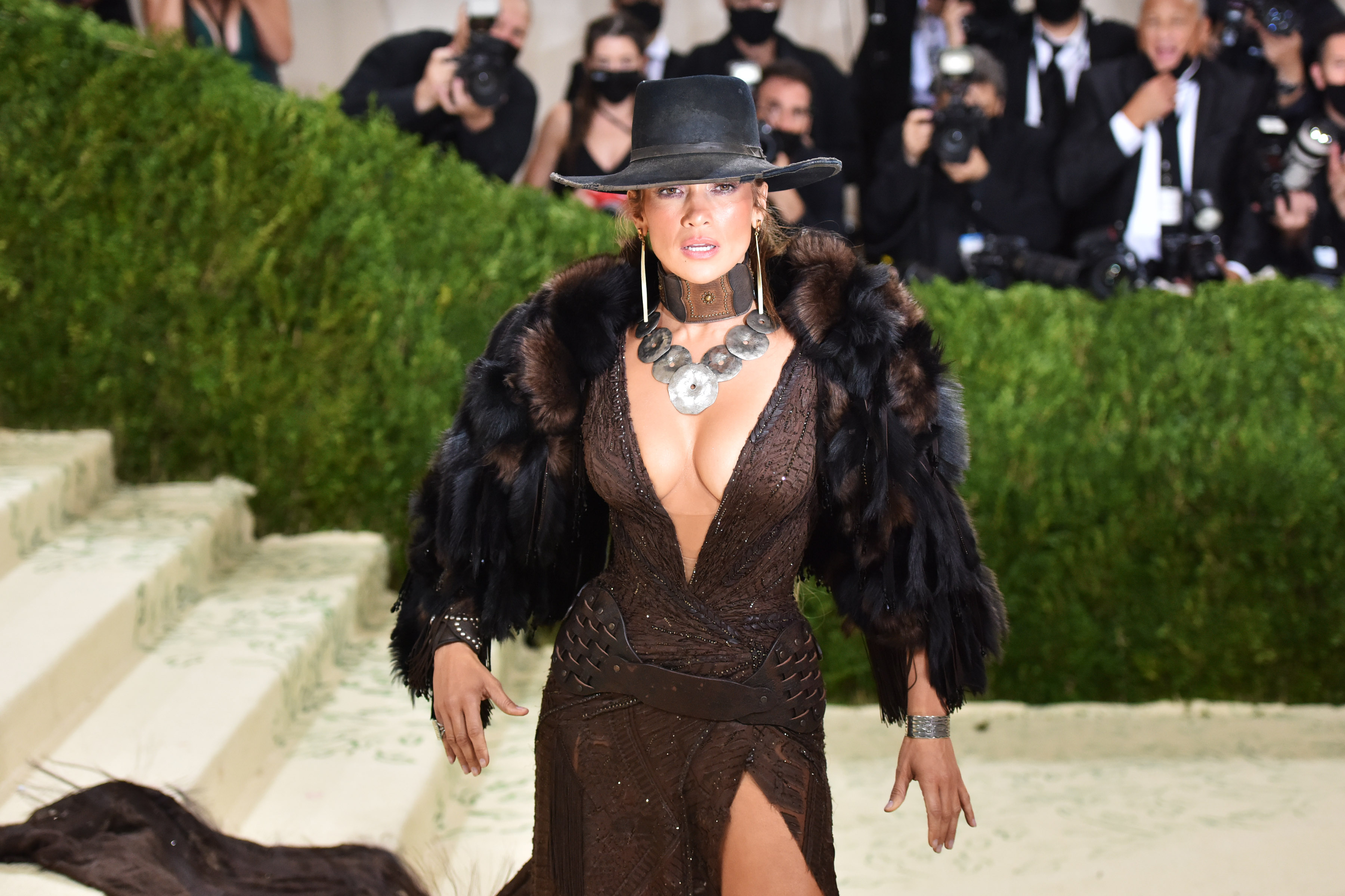 Jennifer Lopez poses in a black hat and tight, brown dress