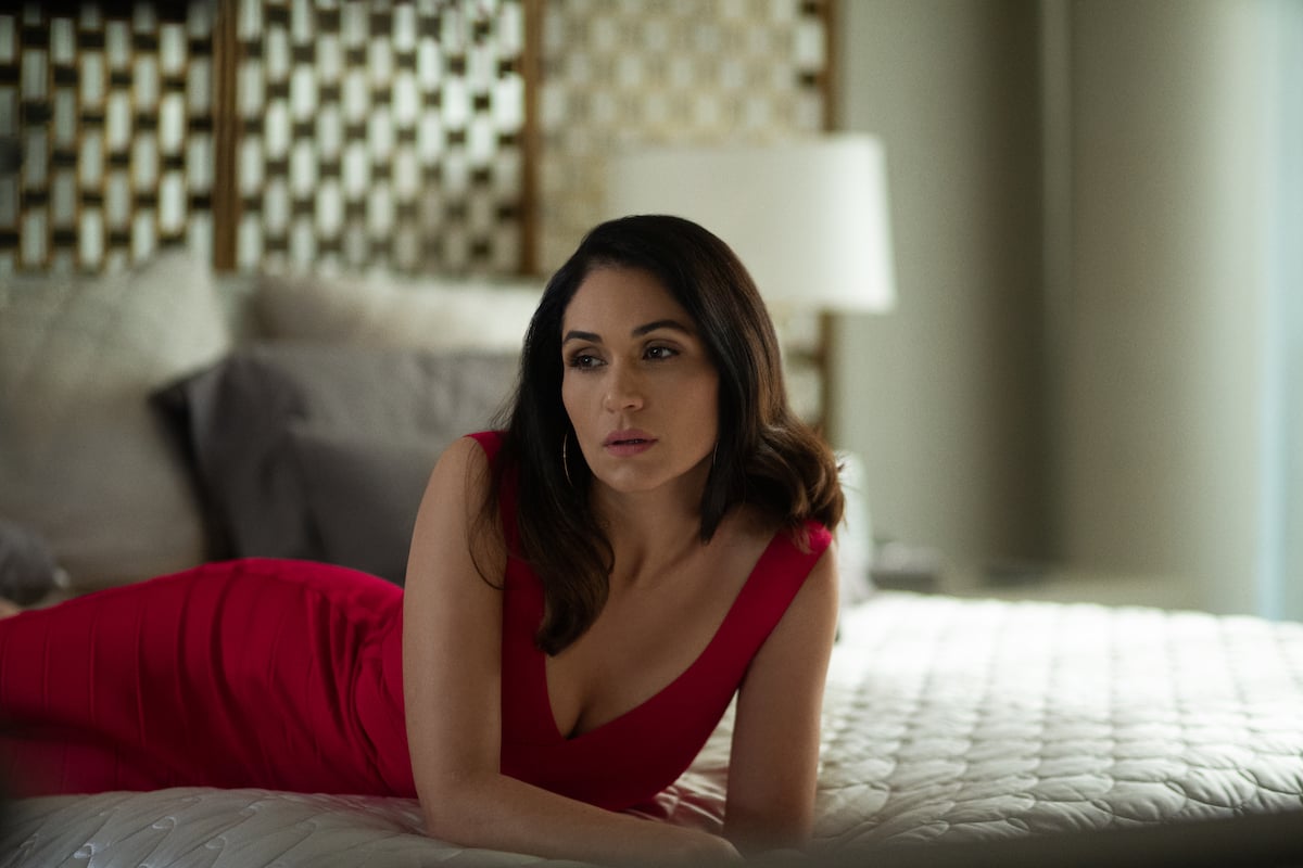 Lela Loren as Angela Valdez in a red dress sprawled on a bed on 'Power'