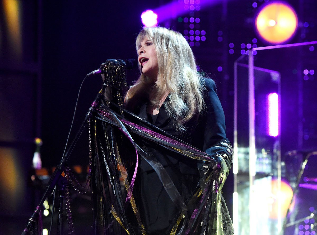 Stevie Nicks sings into a microphone on stage.