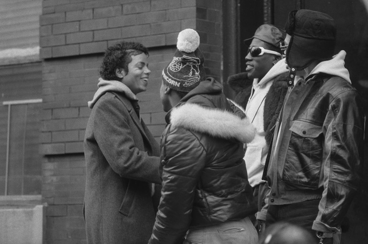 Wesley Snipes and Michael Jackson smiling at each other among a small crowd.