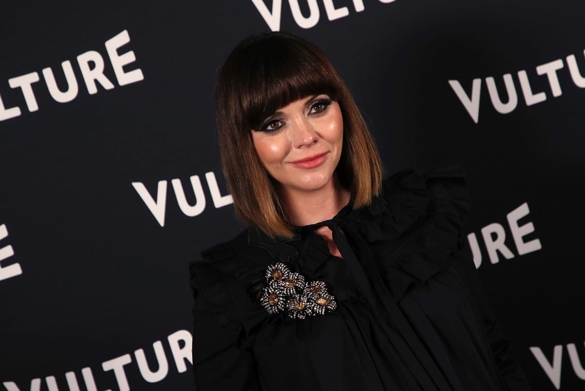 Christina Ricci smiling in a black dress.