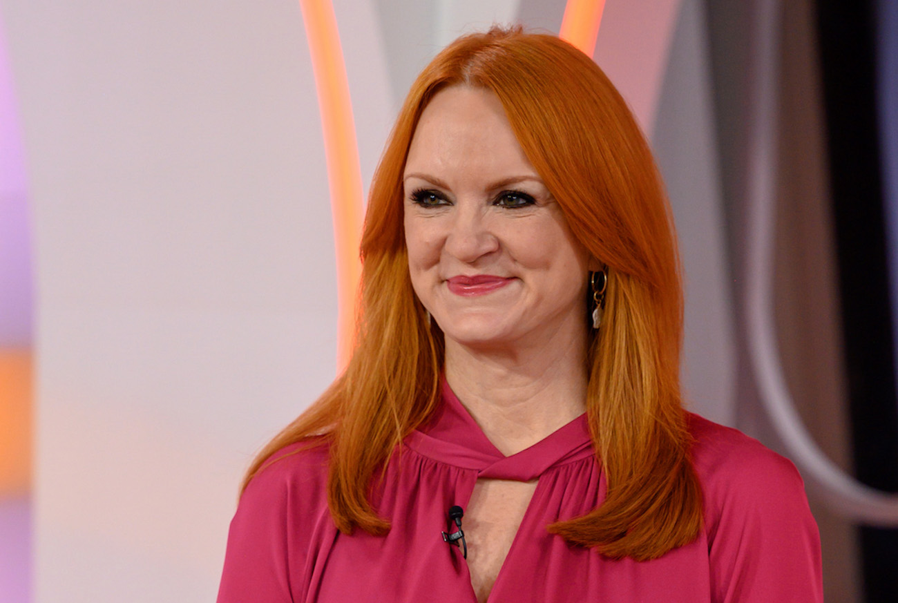 Ree Drummond smirks as she looks on wearing a pink top