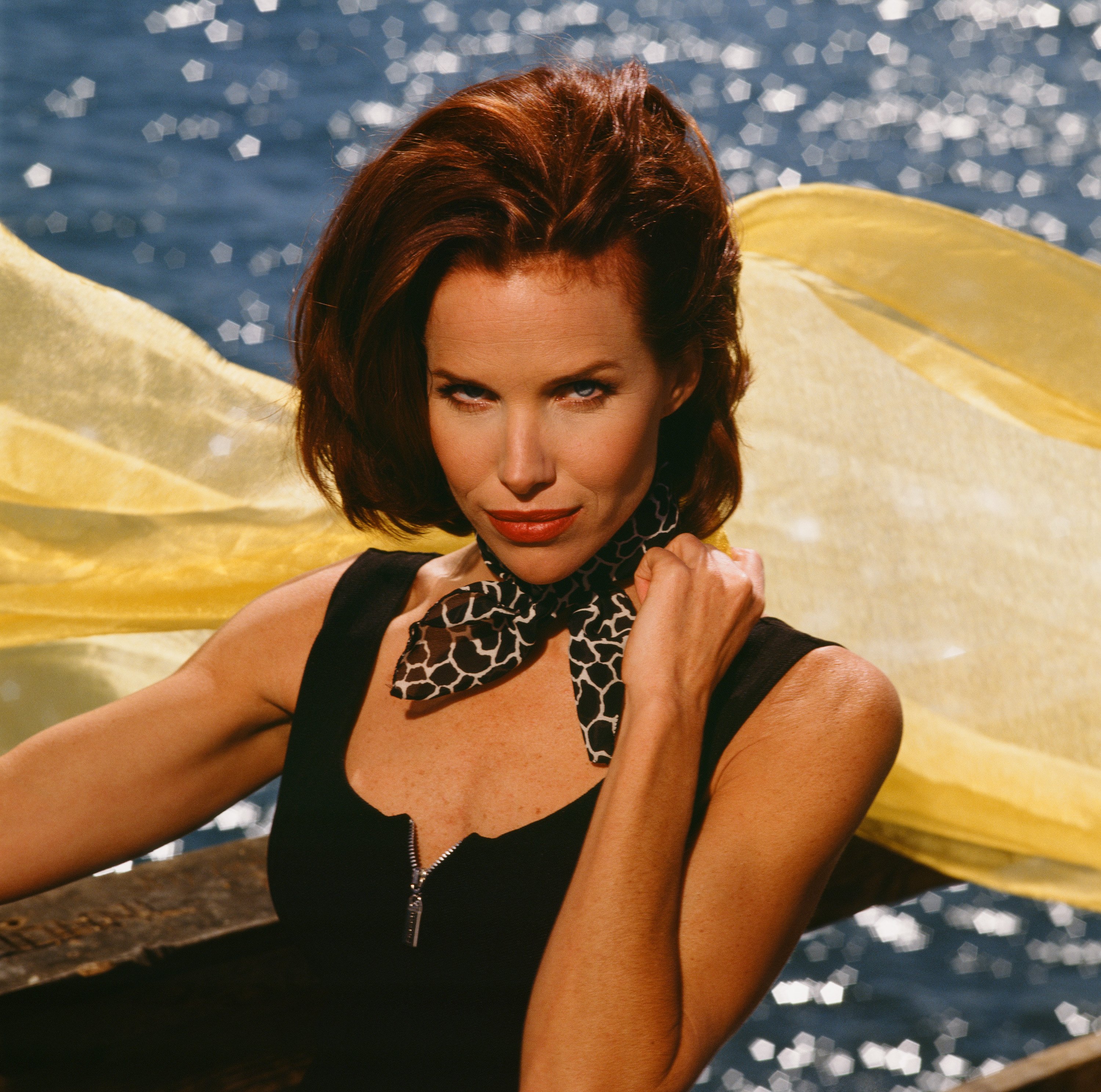 'Sunset Beach' actor Sarah Buxton wearing a black dress and leopard scarf; and standing on a pier.
