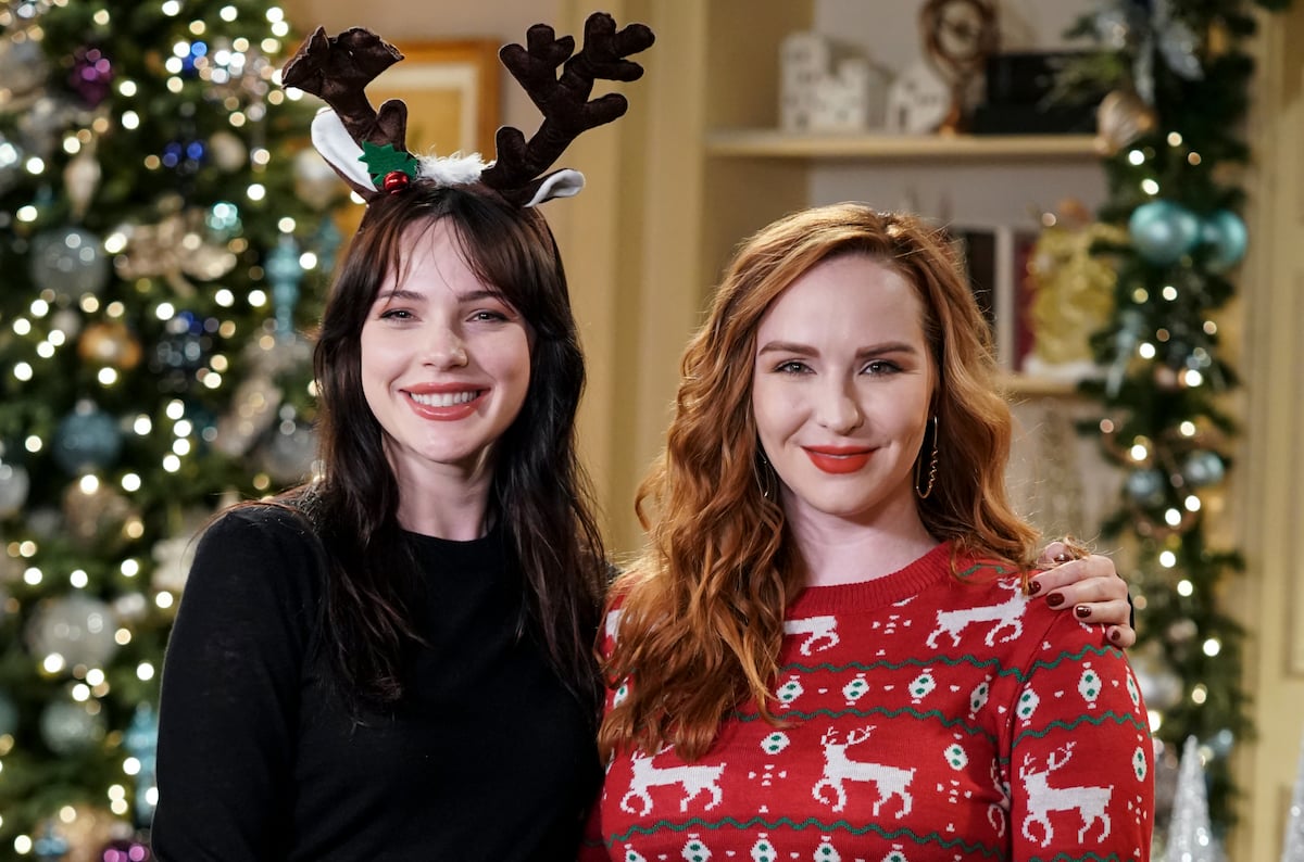 Cait Fairbanks as Tessa and Camryn Grimes as Mariah smiling in front of a Christmas tree