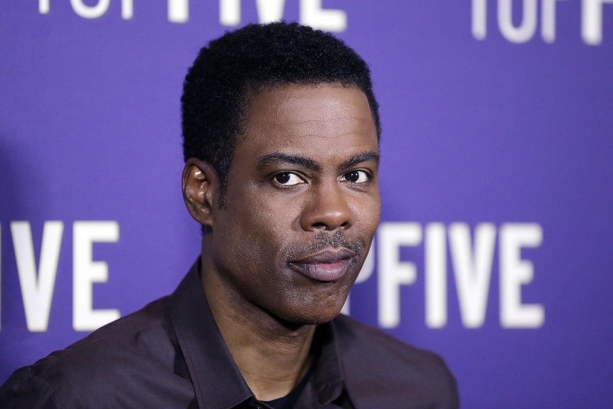 Chris Rock smirking while wearing a jacket.