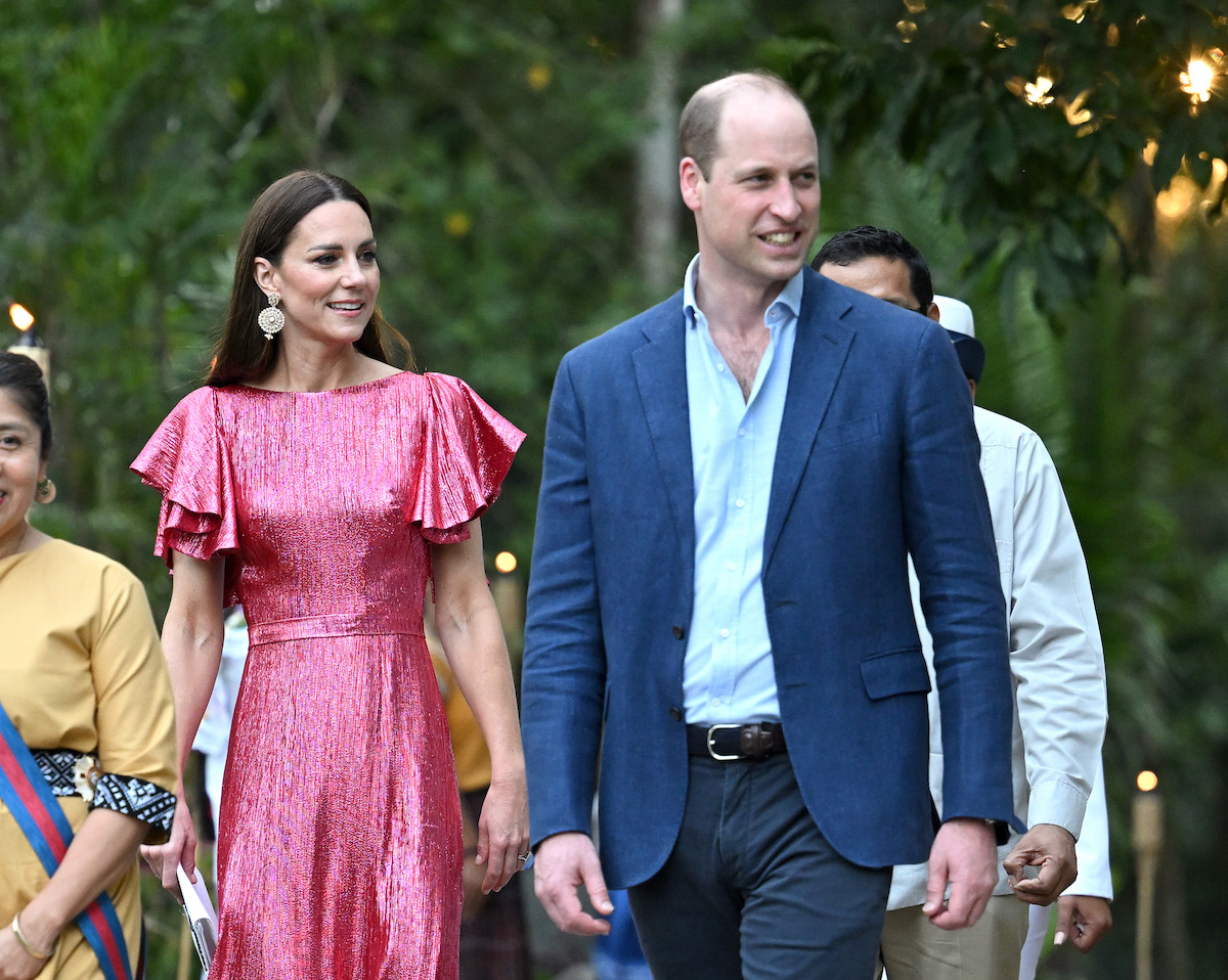 Kate Middleton wears a pink gown as she walks next to Prince William who wears a blue shirt and blazer