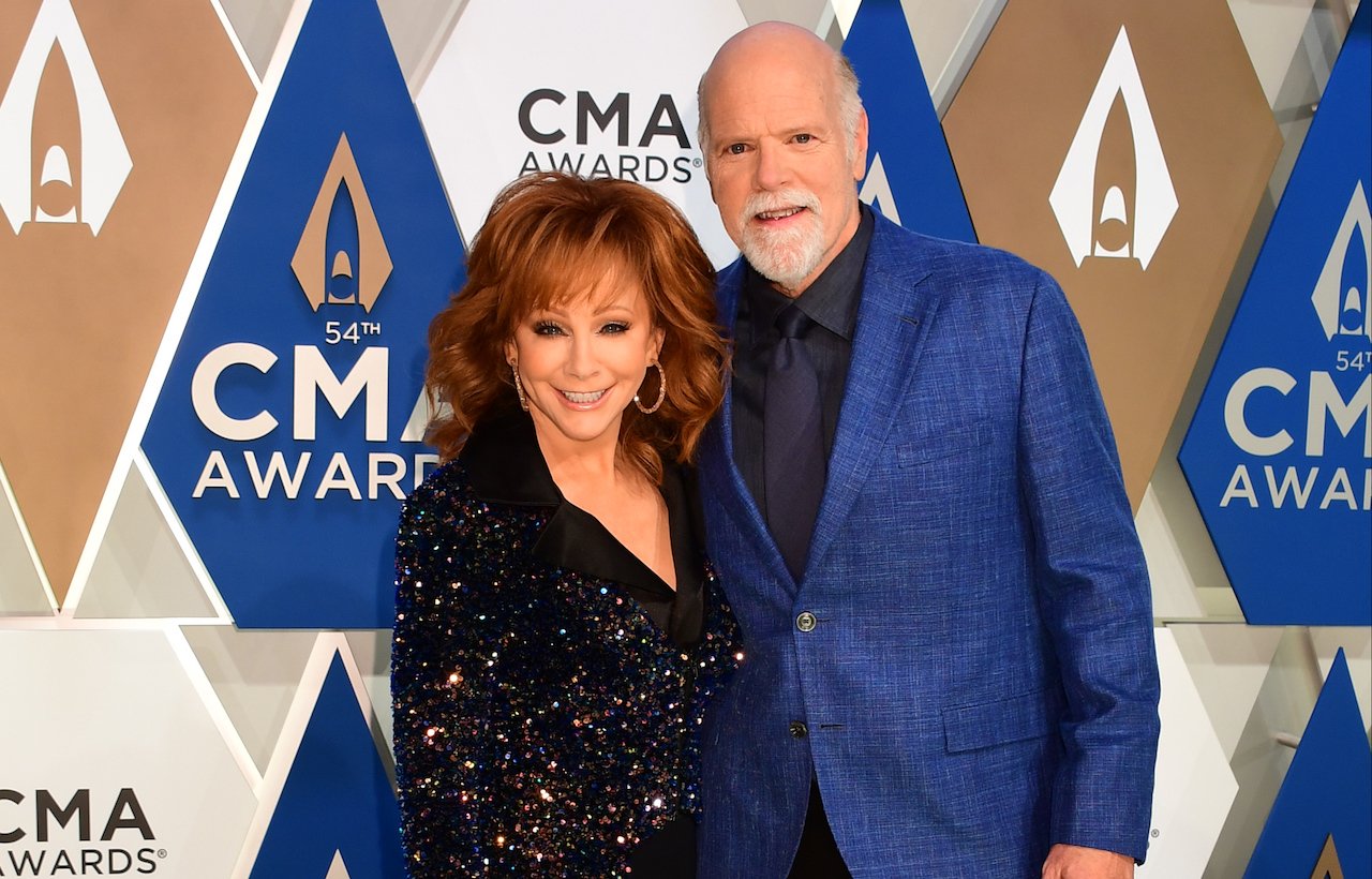 Reba McEntire in black standing next to Rex Linn, who is wearing a blue jacket