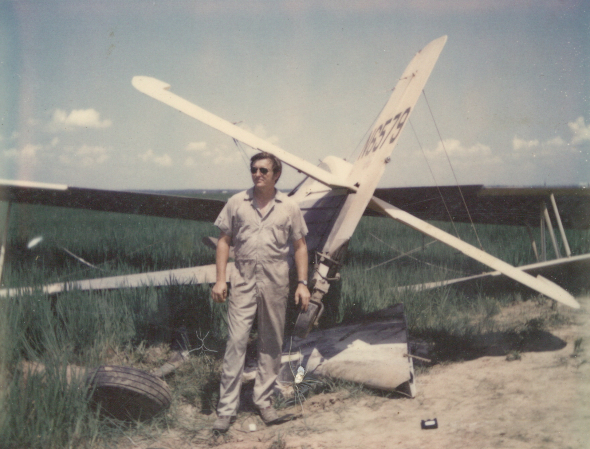 Gary Betzner, the subject of the HBO docuseries 'The Invisible Pilot,' wearing sunglasses and standing in front of a crashed plane.