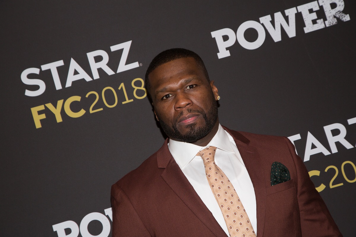 50 Cent posing while wearing a brown suit.