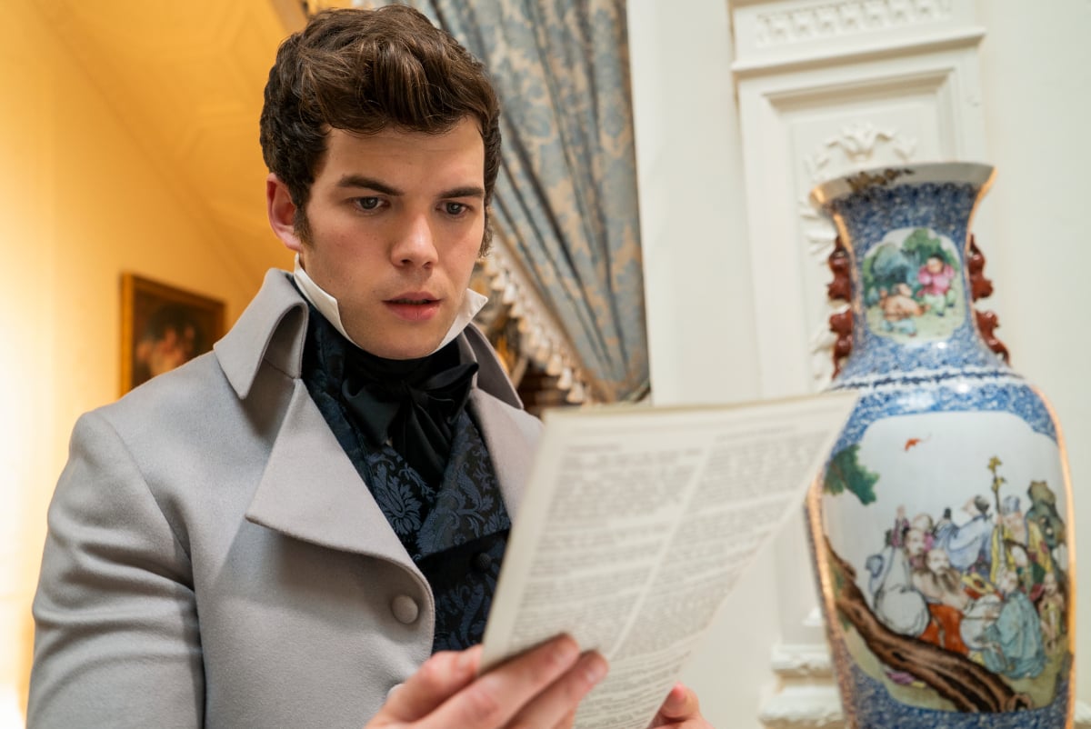 Luke Newton as Colin Bridgerton reading a Lady Whistledown pamphlet. 