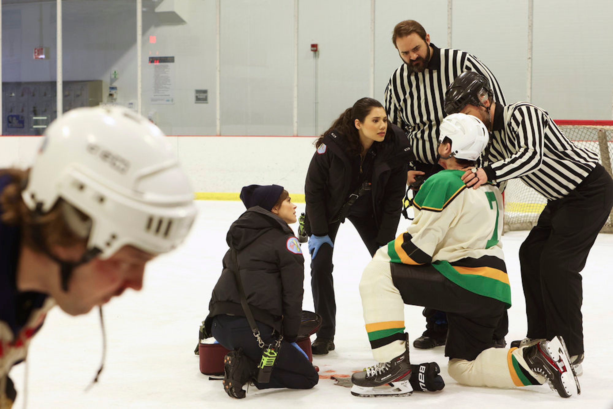 Caitlin Carver as Emma Jacobs and Hanako Greensmith as Violet Mikami in an ice skating rink treating an injured skater in 'Chicago Fire' Season 10 Episode 17