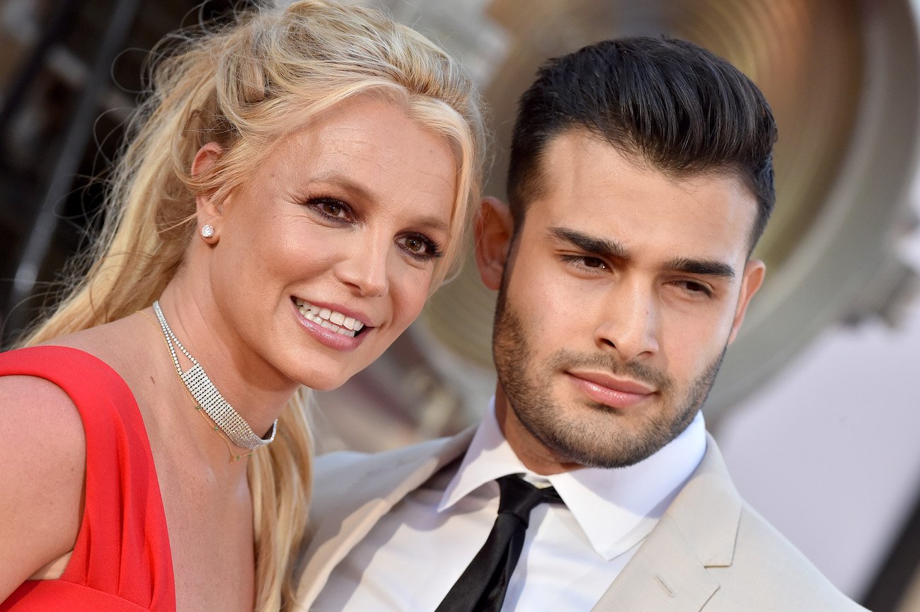 Britney Spears and Sam Asghari standing next to each other and looking toward the right side of the picture
