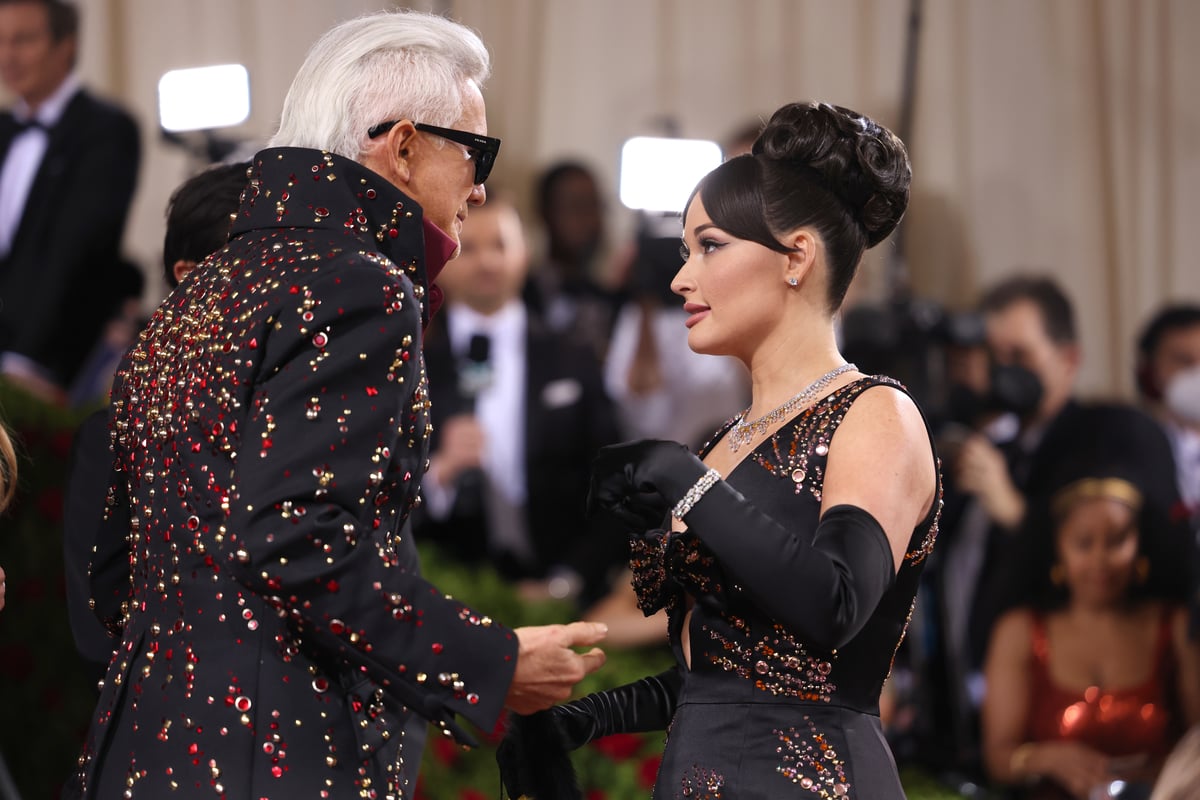 Wearing matching black outfits Baz Lurhmann and Kacey Musgraves talk on the red carpet of the Met Gala in New York, NY.