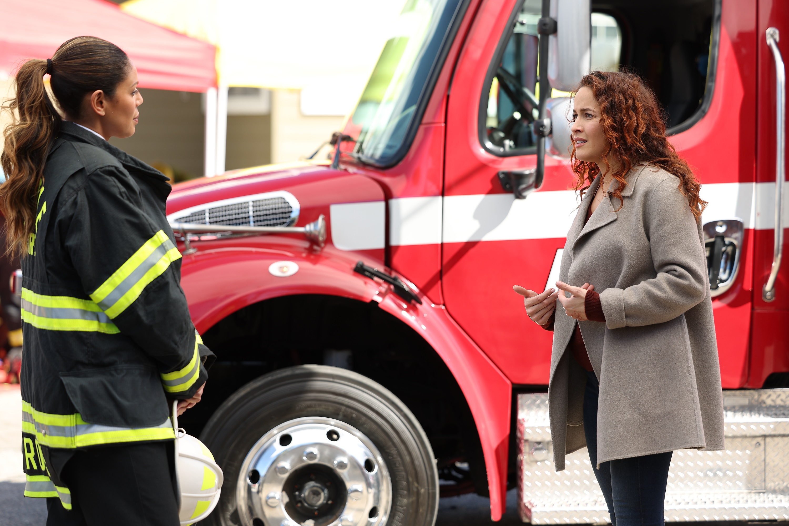 'Station 19' cast members Merle Dandridge and Jaina Lee Ortiz talk in front of a fire truck as Natasha Ross and Andy Herrera