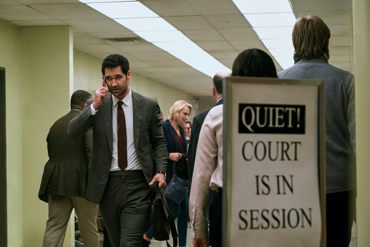 Manuel Garcia-Rulfo as Mickey Haller talking on cell phone in courthouse hallway in Netflix's 'The Lincoln Lawyer'