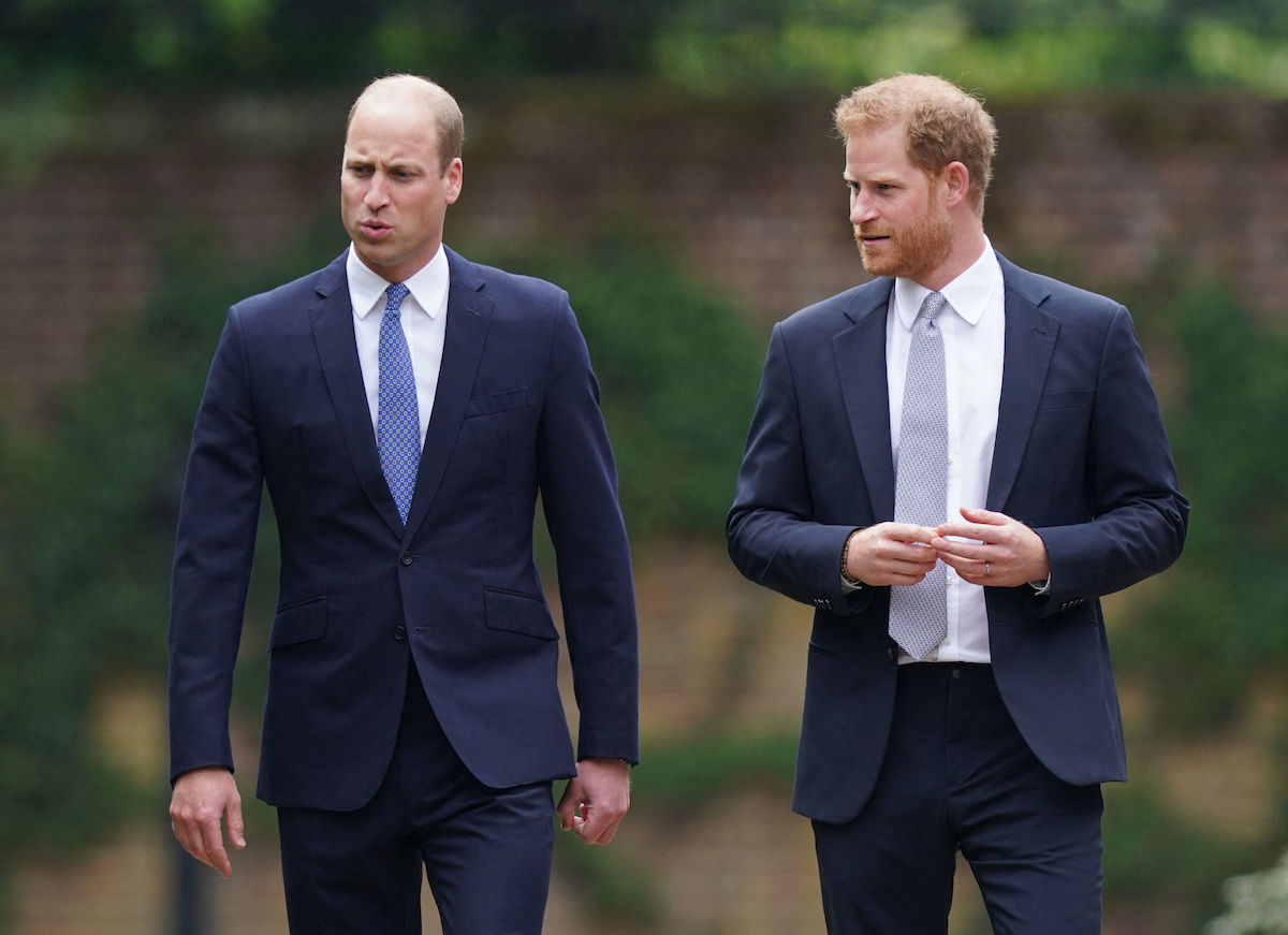 Prince William and Prince Harry walk together both dressed in dark suits and ties