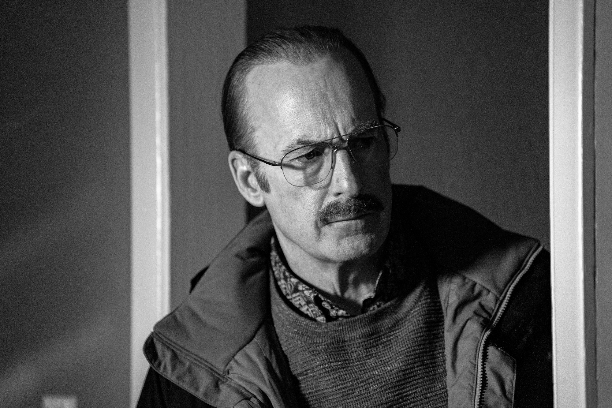 Bob Odenkirk as Gene Takovic in 'Better Call Saul' Season 6 Episode 12. The image is in black and white, and he's wearing glasses and a jacket.