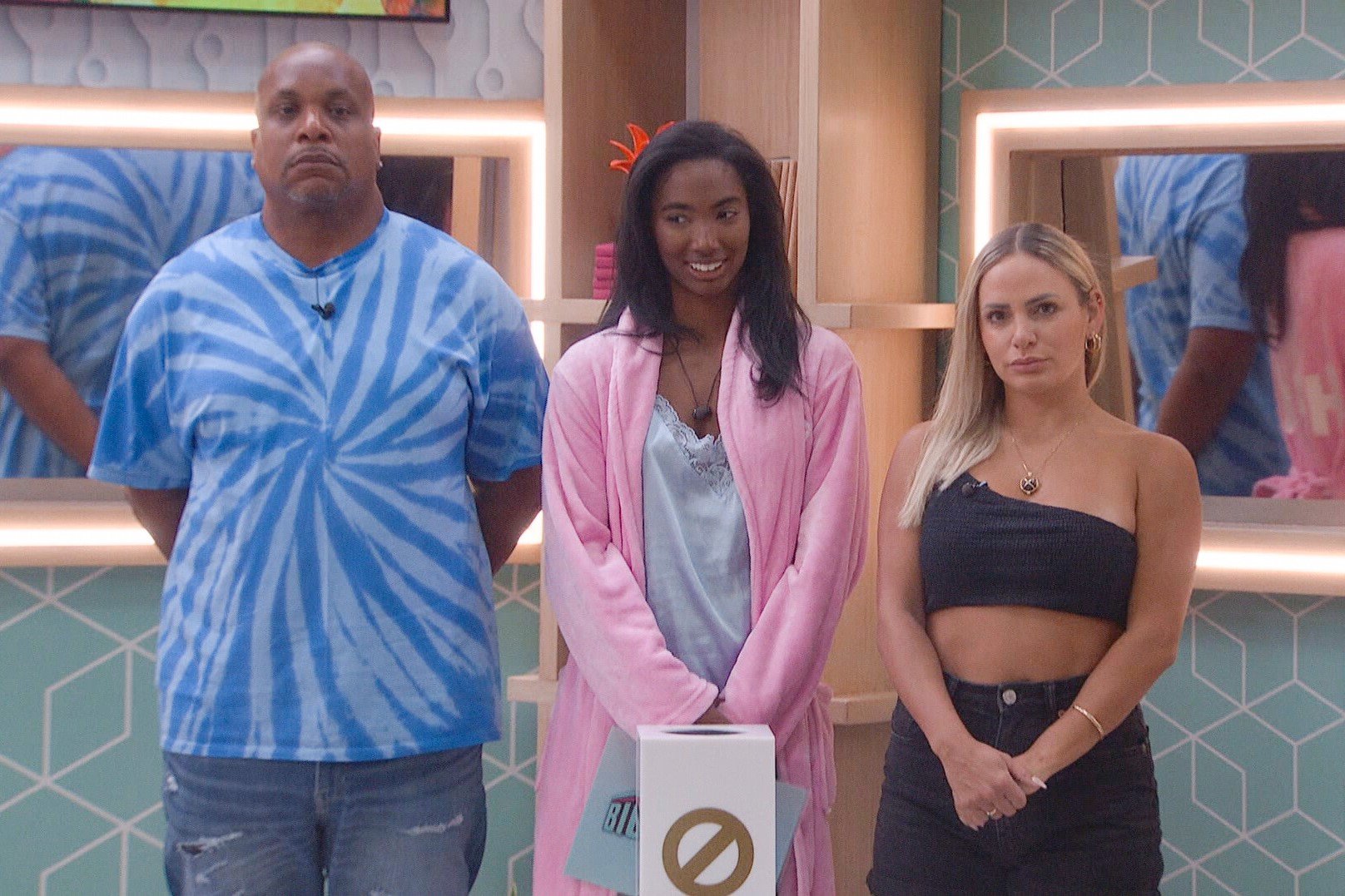 Terrance Higgins, Taylor Hale, and Indy Santos compete in 'Big Brother 24' on CBS, and according to spoilers, either Terrance or Indy will leave the house on Aug. 18. Terrance wears a blue tie dye shirt and jeans. Taylor wears a pink robe over a light blue nightgown. Indy wears a black crop top and black shorts.